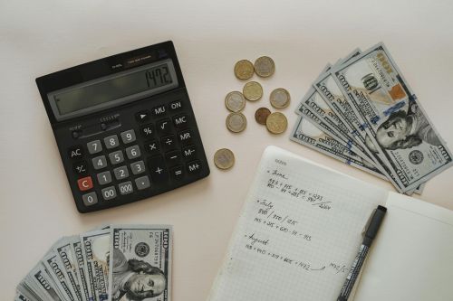 Flat lay of calculator, cash, coins, and handwritten notes for budget planning.