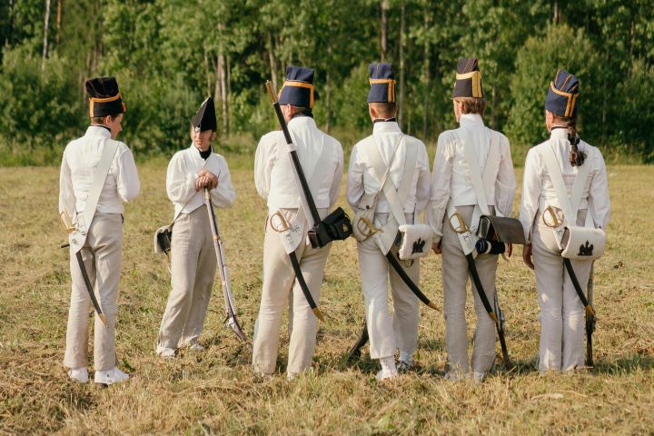Group of soldiers in historical uniforms participating in a reenactment outdoors.