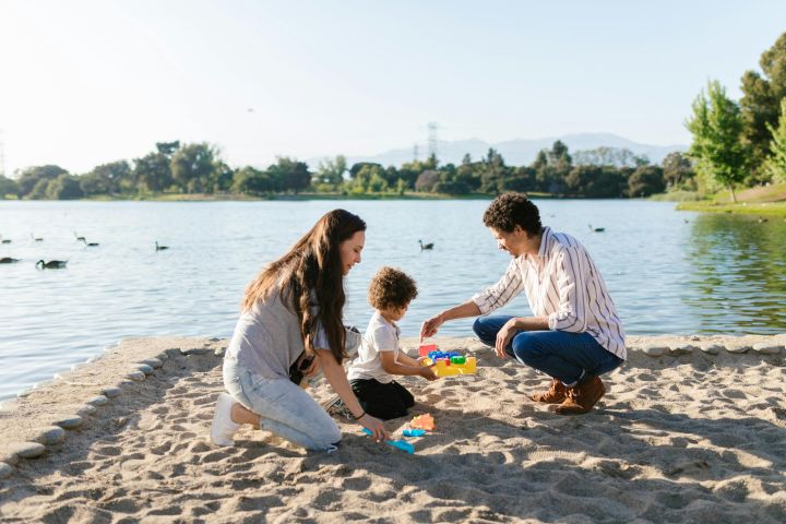 Family playing with toys at the lake on a sunny day, creating fun memories.