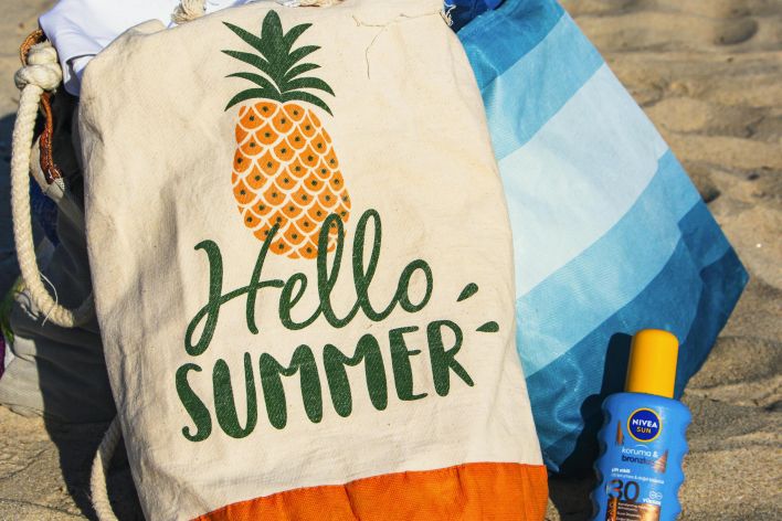 Colorful beach bag and sunscreen evoke a vibrant summer vibe on the sandy beach.