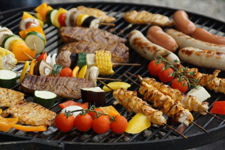 A vibrant assortment of grilled meats, sausages, and vegetables on a barbecue grill.
