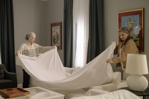 Two women collaborate in making a bed, showcasing teamwork across generations.